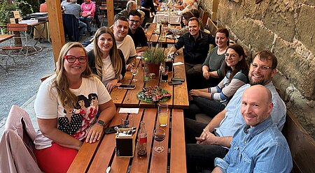 Mehrere Personen sitzen zusammen am Tisch.