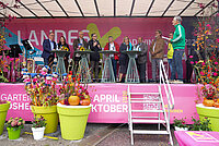 Prominente Persönlichkeiten auf einer pink gestalteten Bühne mit Plfanzen davor und einer Treppe 