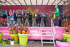 Prominente Persönlichkeiten auf einer pink gestalteten Bühne mit Plfanzen davor und einer Treppe 