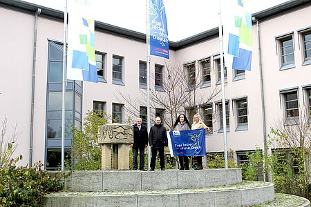 Vier Personen stehen vor dem Landratsamt unter Flagge