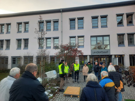 Gruppe vor dem Landratsamt-Gebäude mit Personen in Warnwesten auf gepflastertem Platz – Fahrräder und Holzpodest sichtbar, deutet auf eine organisierte Veranstaltung oder Führung im öffentlichen Verwaltungsbereich.