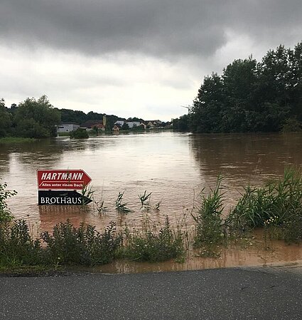 Überflutete Straße, Wegweiser, der mitten im Hochwasser steht