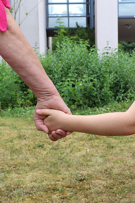 Hand einer Frau hält die Hand eines Kindes.